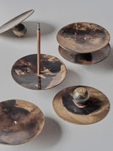 Collection of handmade brass incense burners by 13 Knives with 3mm incense holes and natural flame patina, displayed in a studio detail image