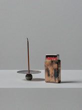 Handmade brass incense holder with burning stick and patinated brass matchbox cover by 13 Knives, displayed on a minimal grey surface