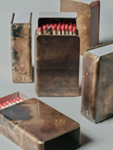Multiple handmade brass matchbox holders by 13 Knives with Redheads matches, showing patina variations and striker detail