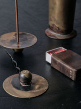 Handmade brass incense burner and patinated brass matchbox holder by 13 Knives displayed together on a dark surface