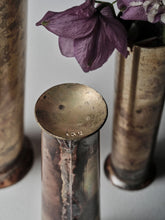Detail of handmade brass vase by 13 Knives showing patina, brazed seam, and stamped base with floral stems