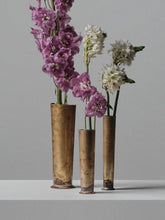 Set of three handcrafted brass vases by 13 Knives Melbourne holding seasonal flowers on a minimal backdrop