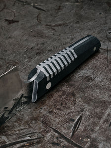 detail shot of a hand forged chef knife with silver inlays in the handle